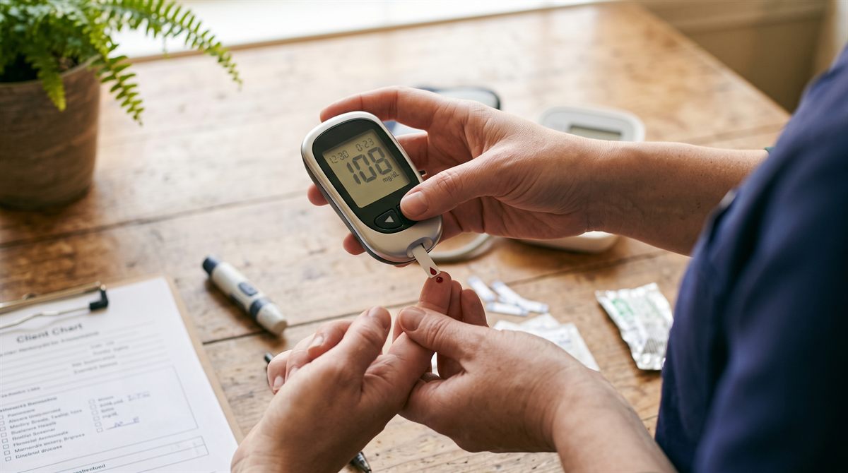 A nurse in navy scrubs taking an older person's blood pressure at home